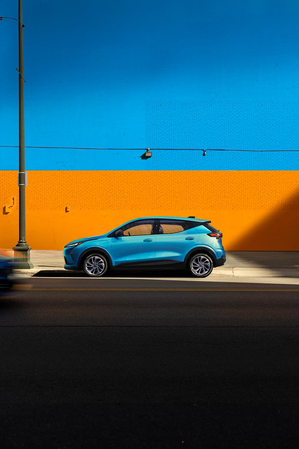 2027 Chevrolet Bolt Parked in Front of an Orange Wall.