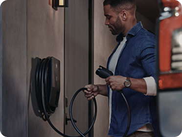 Un hombre sostiene un cargador de pared de Chevy EV