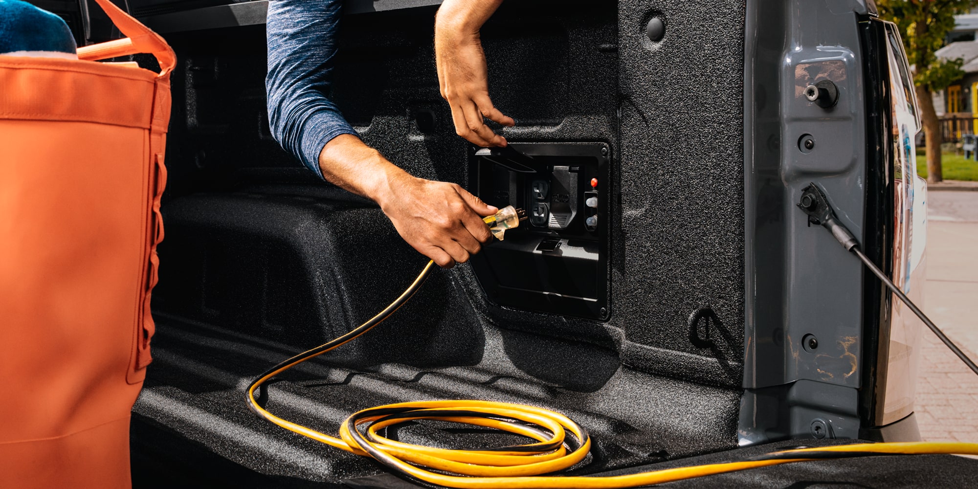 A Man Pulling an Extension Cord into the Bed Outlet of the 2026 Chevy Silverado EV