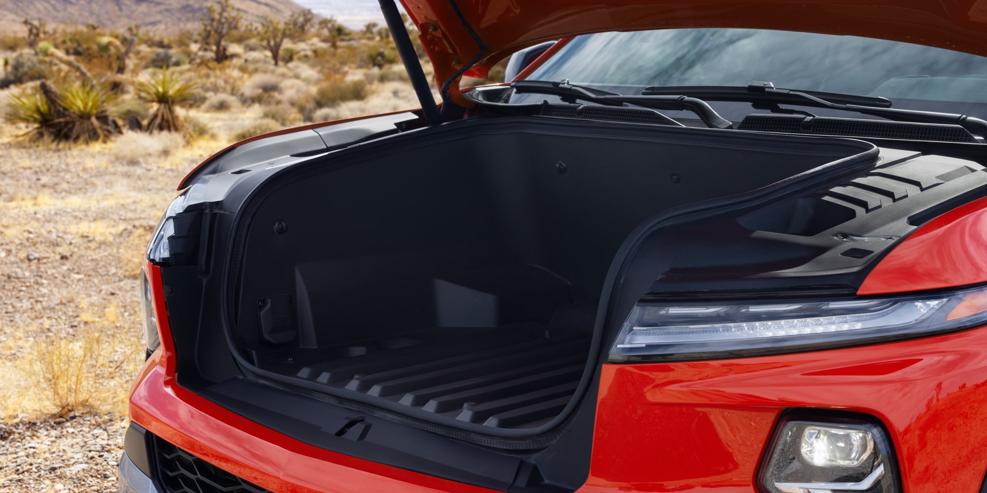 A Front View of a Red Chevy Silverado EV With the Front Storage Compartment Open.
