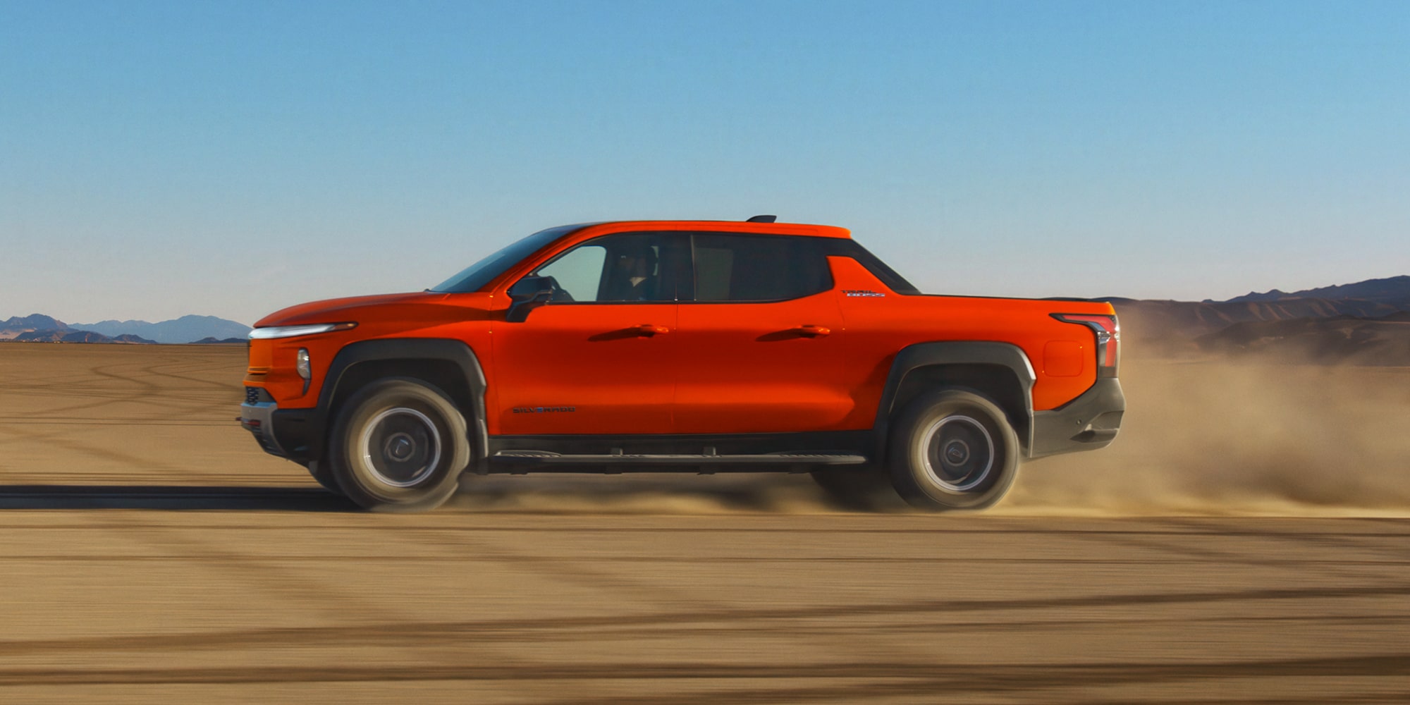 Overhead View of an Orange 2027 Silverado EV Drifting through the Desert with Dust Flying Everywhere