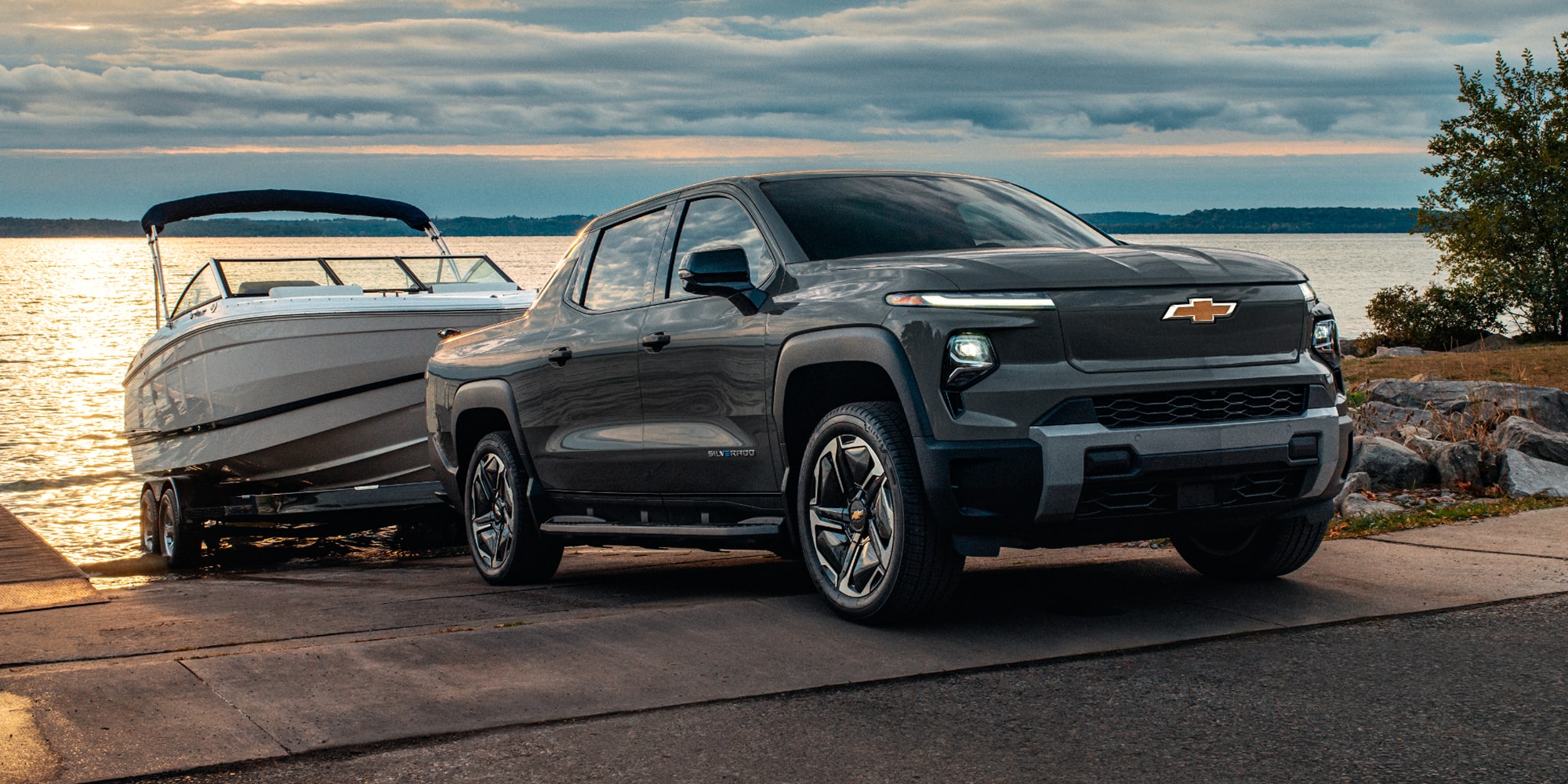 Three Quarters Rear View of an Orange 2027 Silverado EV Driving Down a Desert Road