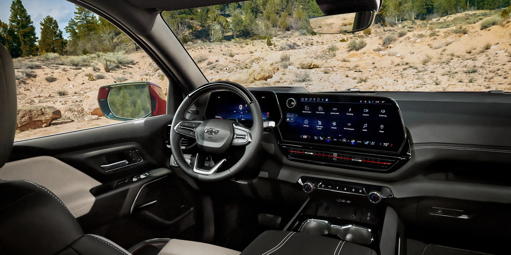 The Interior of a Chevrolet Silverado EV Trail Boss Pickup Truck, Showing a Dual-Screen Digital Instrument Cluster and Infotainment System With a Black and White Leather-Trimmed Steering Wheel and Matching Seats.