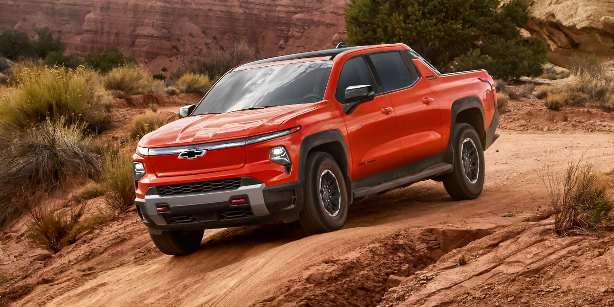 Three Quarters Rear View of a 2026 Chevy Silverado EV Going Down the Road in the Middle of a Desert