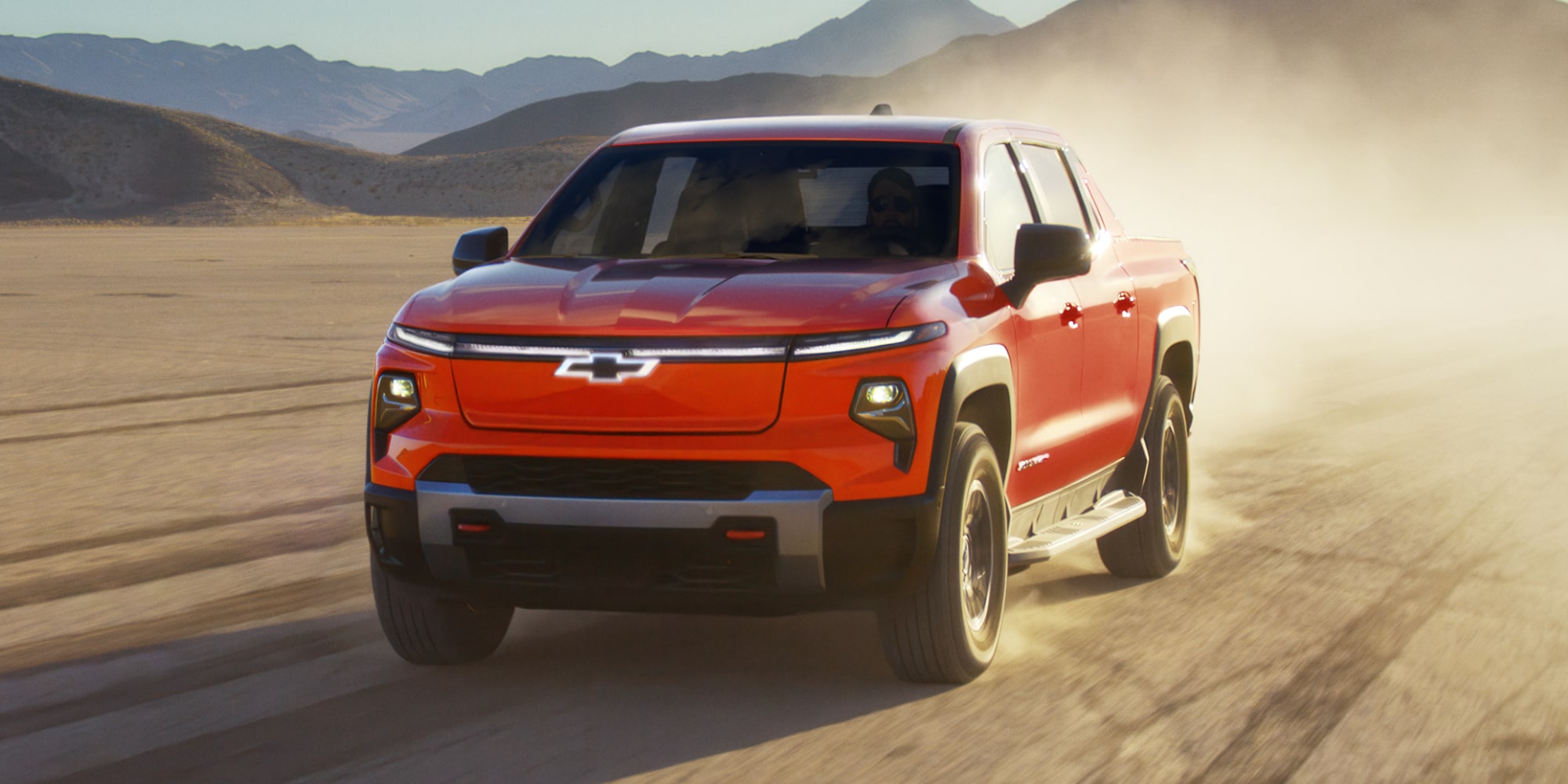 Side View of an Orange 2027 Chevy Silverado EV Driving Down the Desert