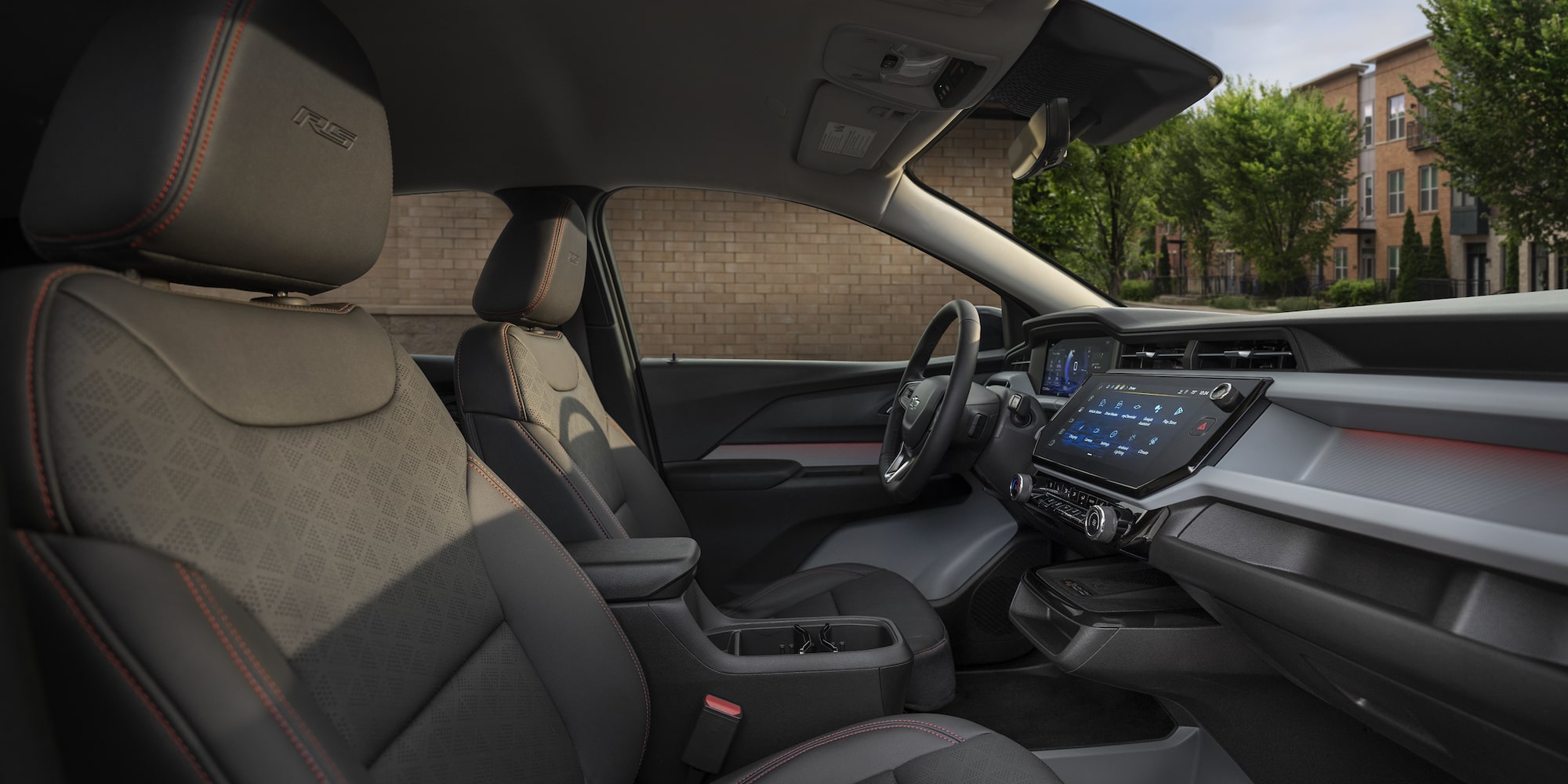 The Sun Shining into the Interior of a 2027 Chevrolet Bolt RS, Showing the Black Evotex Front Seat with Red Stitching and the RS Badge on the Headrest