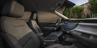 The Sun Shining into the Interior of a 2027 Chevrolet Bolt RS, Showing the Black Evotex Front Seat with Red Stitching and the RS Badge on the Headrest