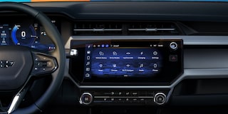 The Interior of a 2027 Chevrolet Bolt Showing the Driver's Perspective of the Digital Dashboard and the Infotainment Screen Displaying App Icons