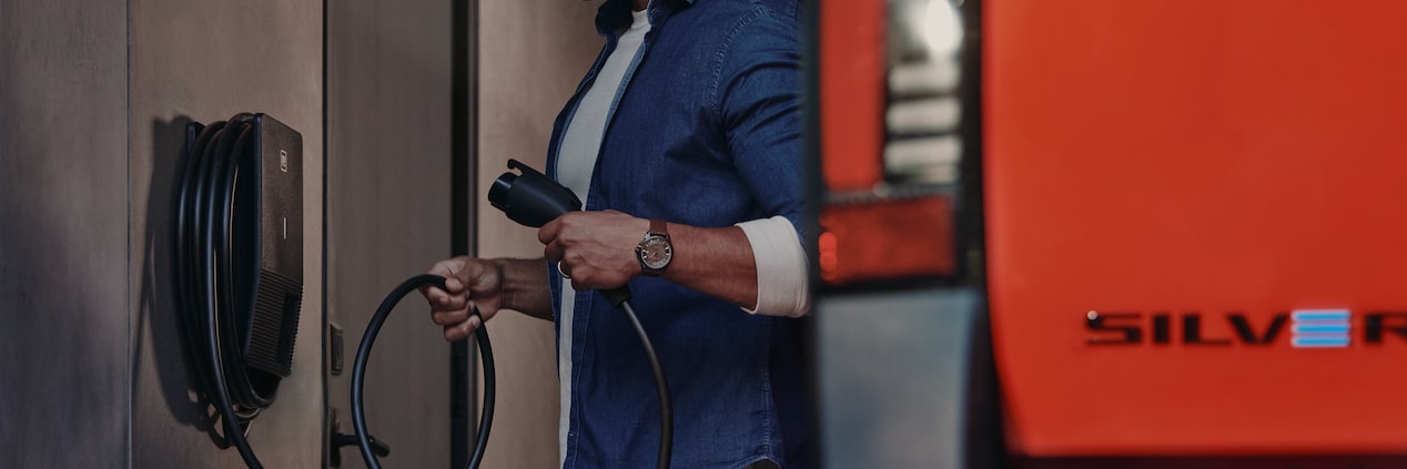 Close-up of Someone Holding a Home EV Charger Cord Next to a Red Silverado EV