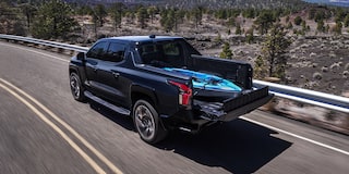 Blue Silverado EV Driving with a Kayak Stored in the Bed of the Truck
