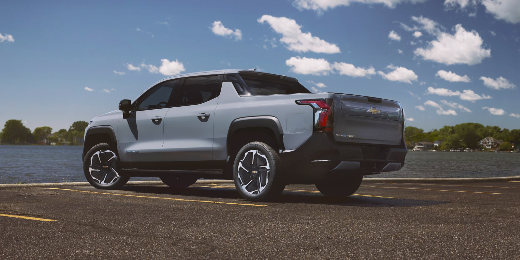 Rear Quarter View of a Gray Chevrolet Silverado EV Parked by a Lake on a Sunny Day.
