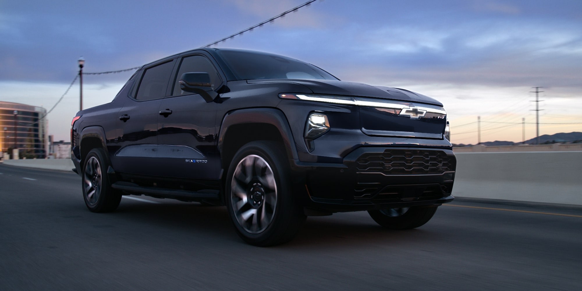 Passenger Side Profile View of a Black Silverado EV Driving at Dusk
