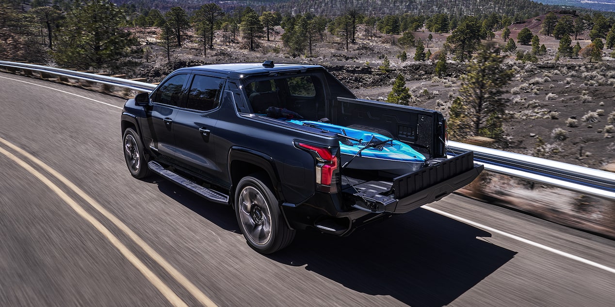 Blue Silverado EV Driving with a Kayak Stored in the Bed of the Truck