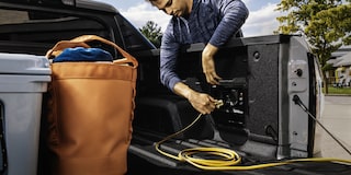 A Man Plugging an Extension Cable into the Outlets in the Bed of the Silverado EV