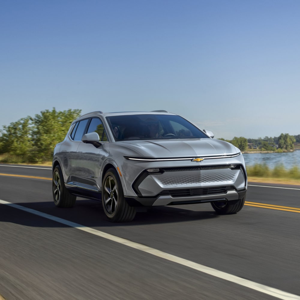 2025 Chevy Equinox EV Driving Down a Road Near a Small Lake