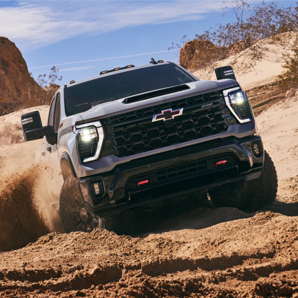 2025 Chevy Silverado HD Driving Through Muddy Terrain in a Western Landscape