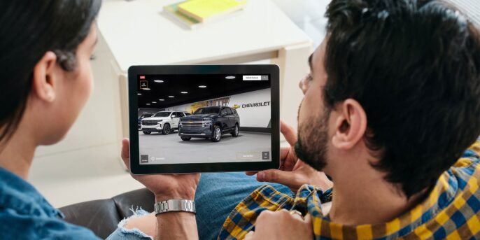 Couple holdding laptop and watching chevy virtual showroom in their house