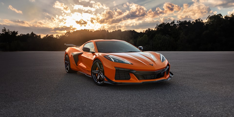 Toma nocturna de un Corvette Z06 naranja estacionado en un camino despejado