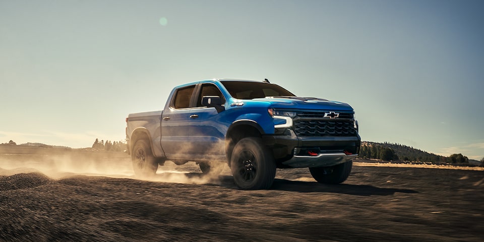 Toma matutina de una Silverado LD azul circulando por un campo despejado