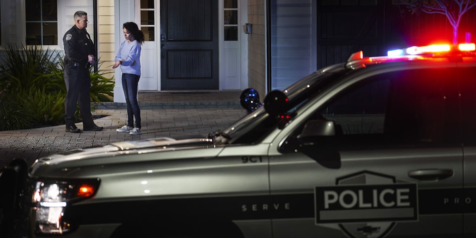 A Woman Speaks with a Police Officer Outside of Her Home