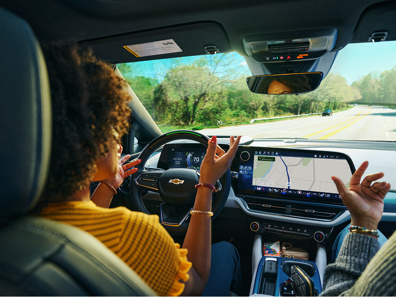 A Woman Talking Hands Free to a Passenger While Driving a Chevy Vehicle Utilizing Super Cruise and Navigation