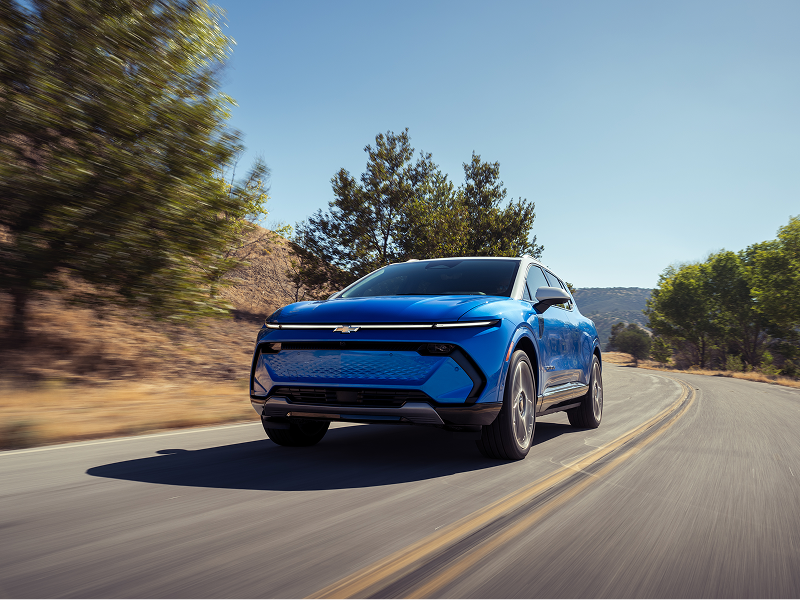 Front View of a Blue Chevy Equinox EUV Driving Down a Mountain Road