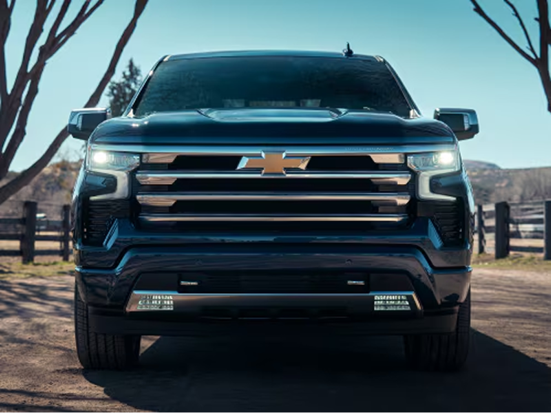 Front View of a Chevy Silverado Truck's Grille with the Headlights On