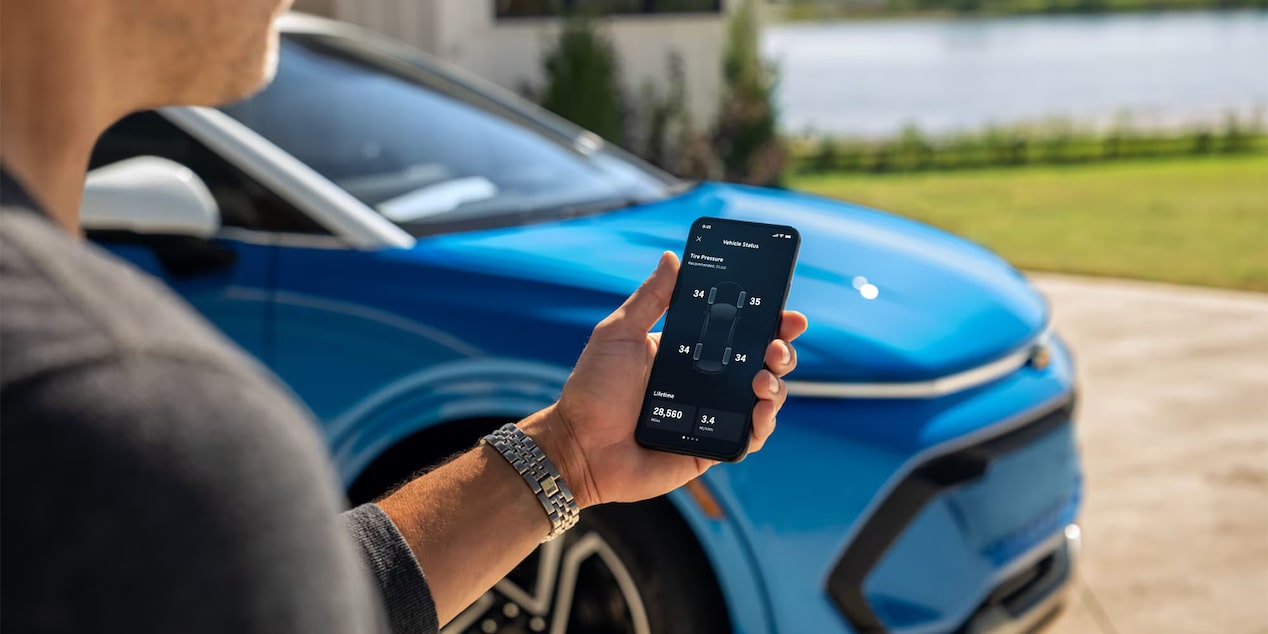 A Man Holds a Phone with the Vehicle Status on the Screen