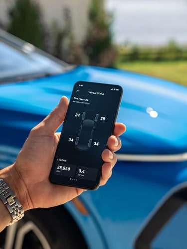 Un hombre sostiene un teléfono con el estado del vehículo en la pantalla