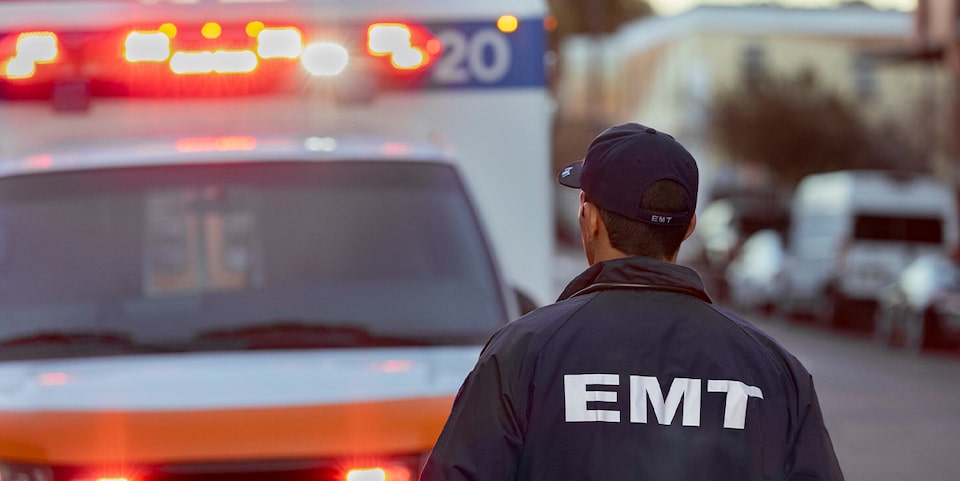 Un técnico en emergencias médicas camina en dirección a una ambulancia