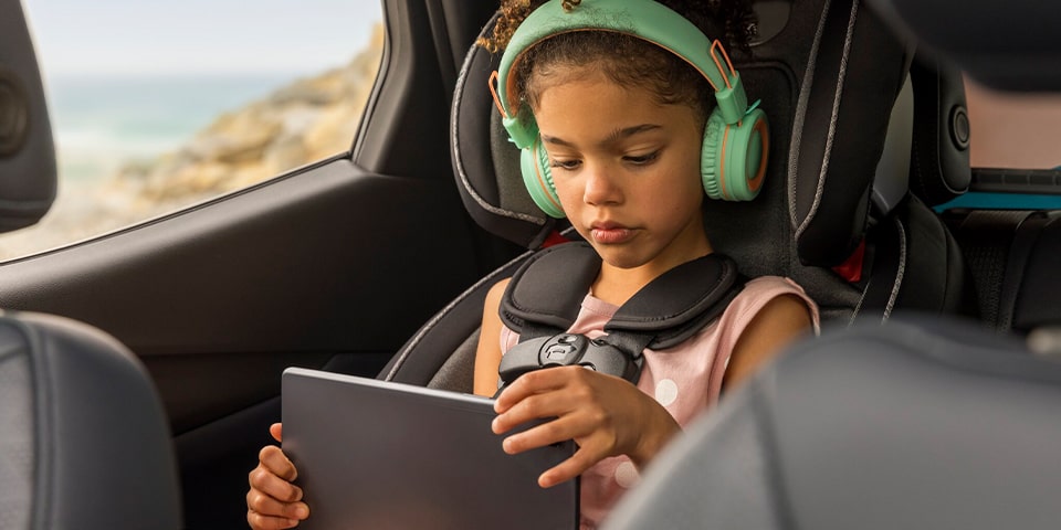 Niño en un asiento del auto jugando con una tableta conectada al Wi-Fi dentro del vehículo