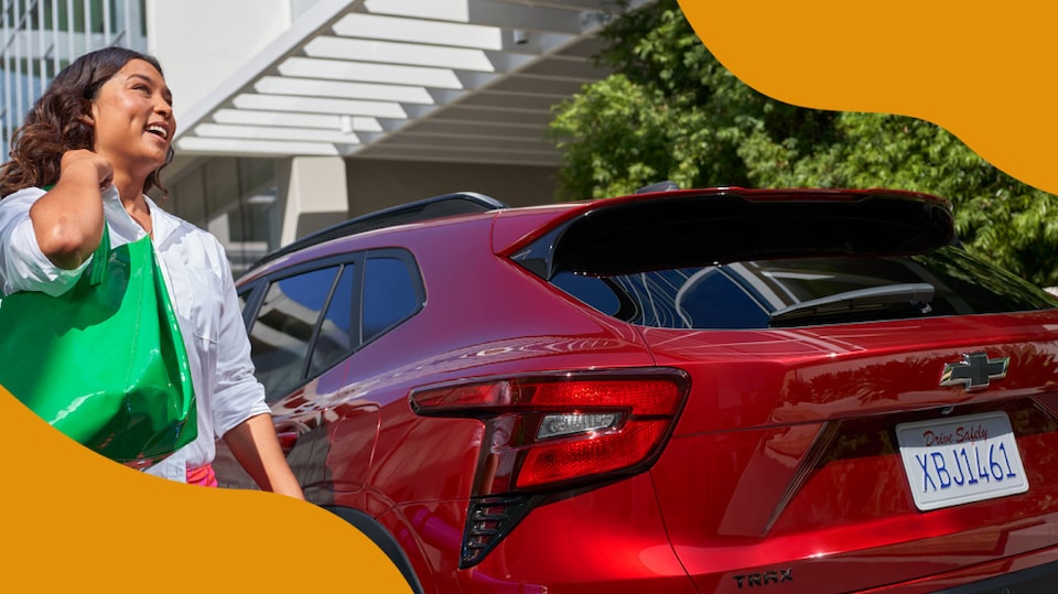 Mujer llevando un bolso verde camina hacia la parte trasera de su Chevy Blazer