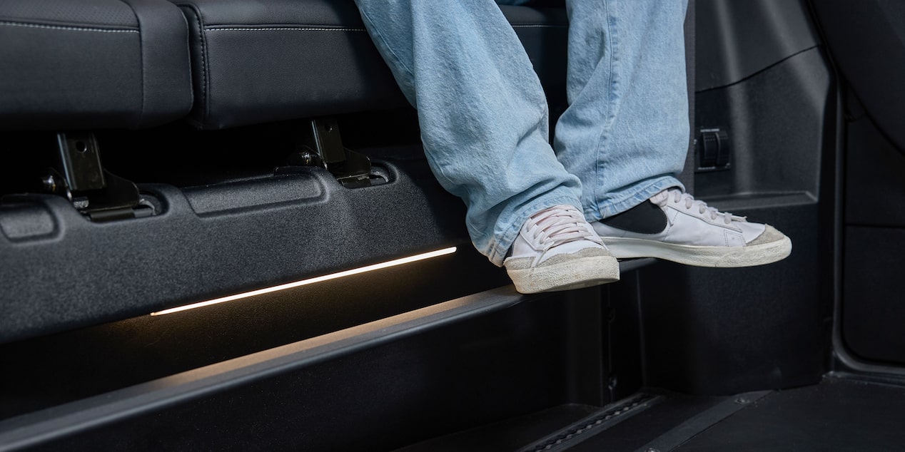 The Interior Floor of a Chevy Traverse SUV Showing a Pair of White Sneakers Resting on a Black Footrest Near the Side Panel.