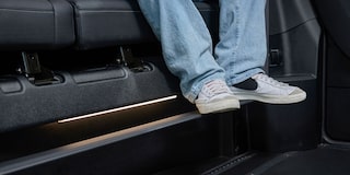The Interior Floor of a Chevy Traverse SUV Showing a Pair of White Sneakers Resting on a Black Footrest Near the Side Panel.