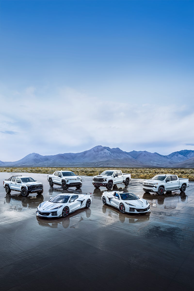 A Collection of Chevrolet Stars and Steel Edition Corvettes and Trucks on a Wet Surface in a Desert.