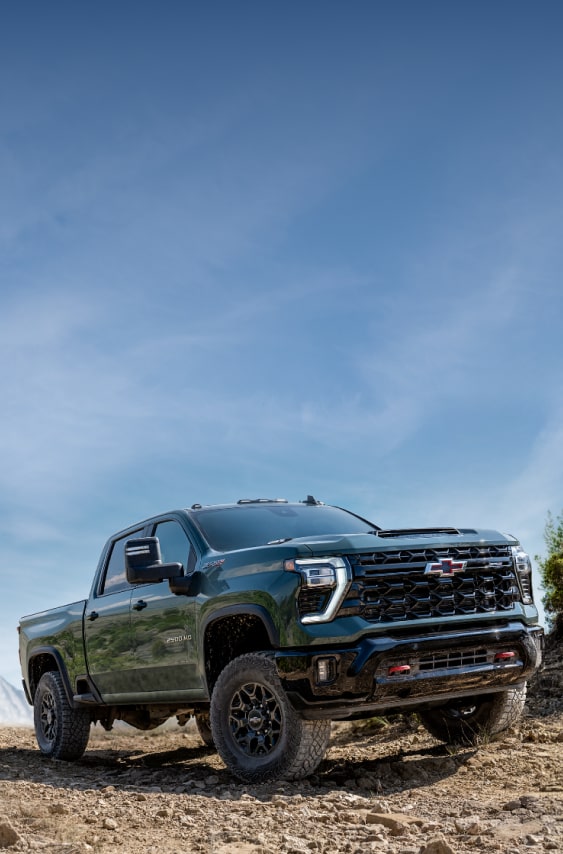 A Black 2027 Chevy Silverado HD Climbing a Rocky Dirt Trail Beneath a Blue Sky