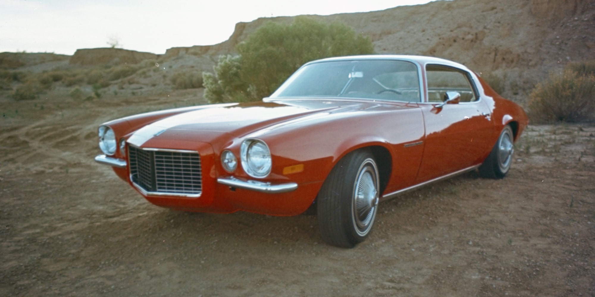 Red Classic Coupe Parked on a Dirt Road in a Desert Landscape