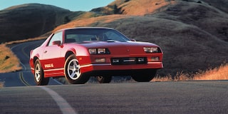 Far Away Front View Shot of a Red Sports Car Going Down the Road