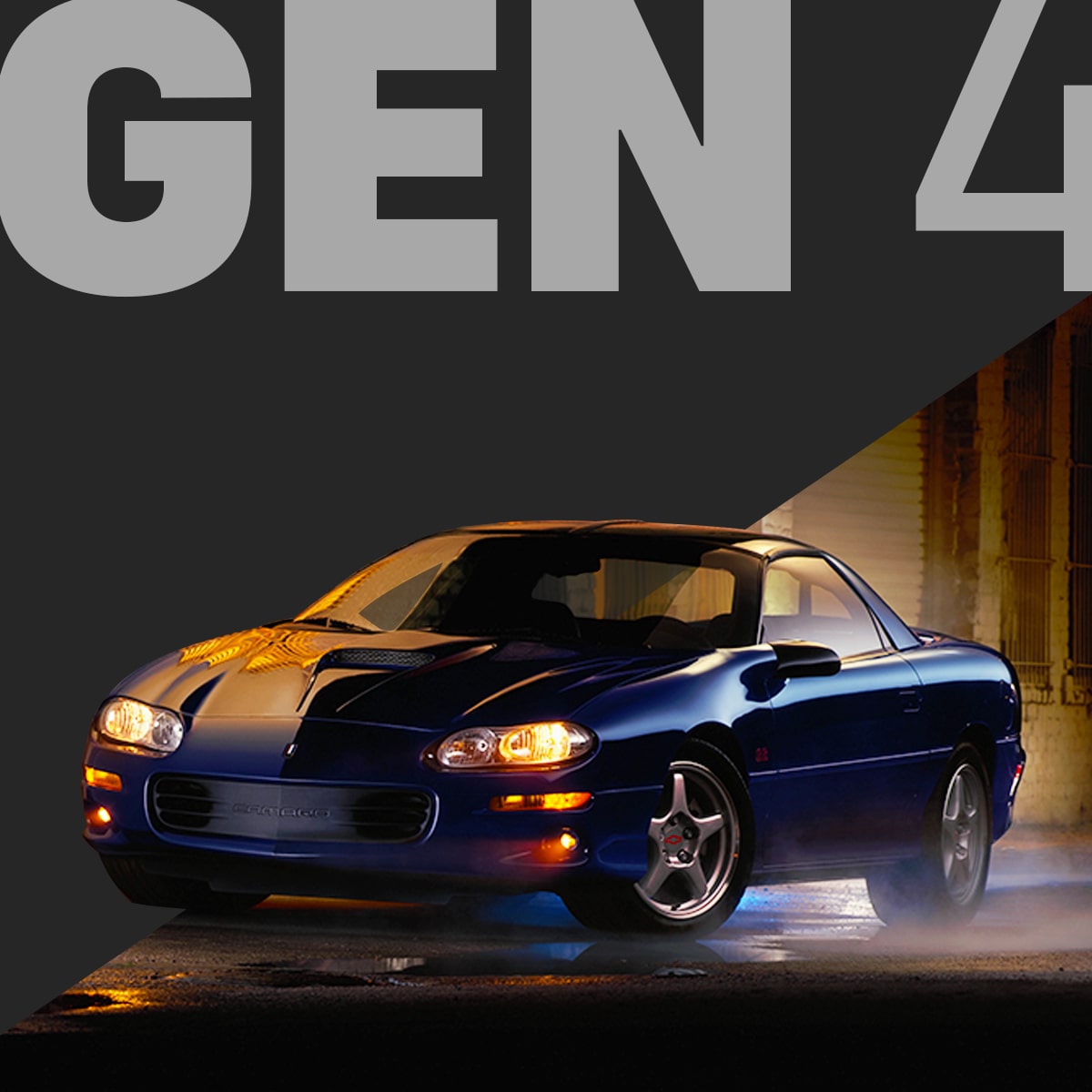 Dark Blue Chevy Camaro at Night with Headlights On, Parked with Warm Yellow Light Reflecting off the Wet Pavement