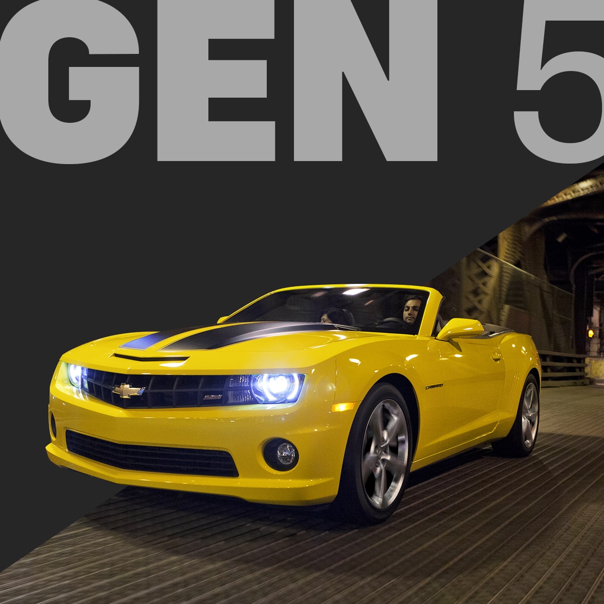 Front Angle View of a Bright Yellow Chevy Camaro Convertible Driving at Night with Its Headlights Glowing