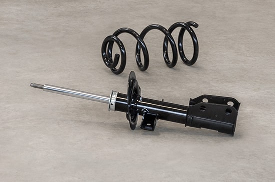 Black Shock Absorber Strut and Matching Coil Spring Laid Out on a Surface