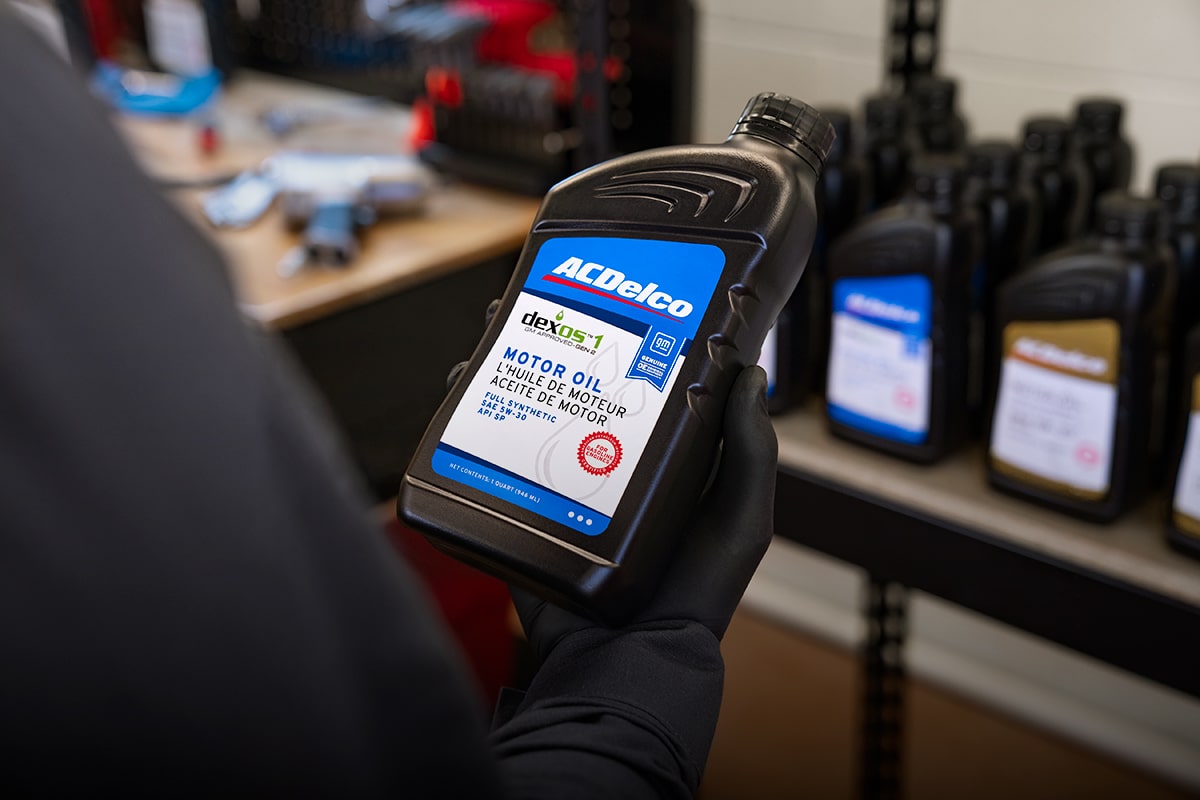 Mechanic Wearing Black Gloves Holding a Bottle of ACDelco Motor Oil in a Workshop