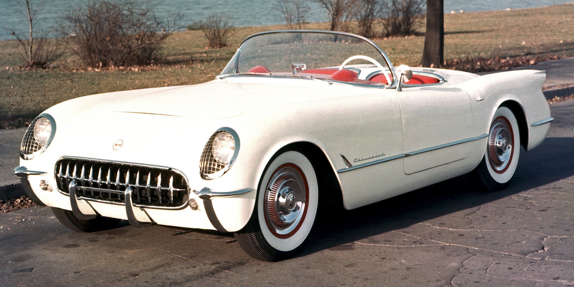 A Front View of a White Classic Chevrolet Corvette Convertible with Chrome Detailing Parked Outdoors.
