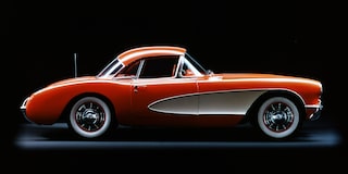A Side View of an Orange and White Classic Chevrolet Corvette Convertible Displayed Against a Black Background.