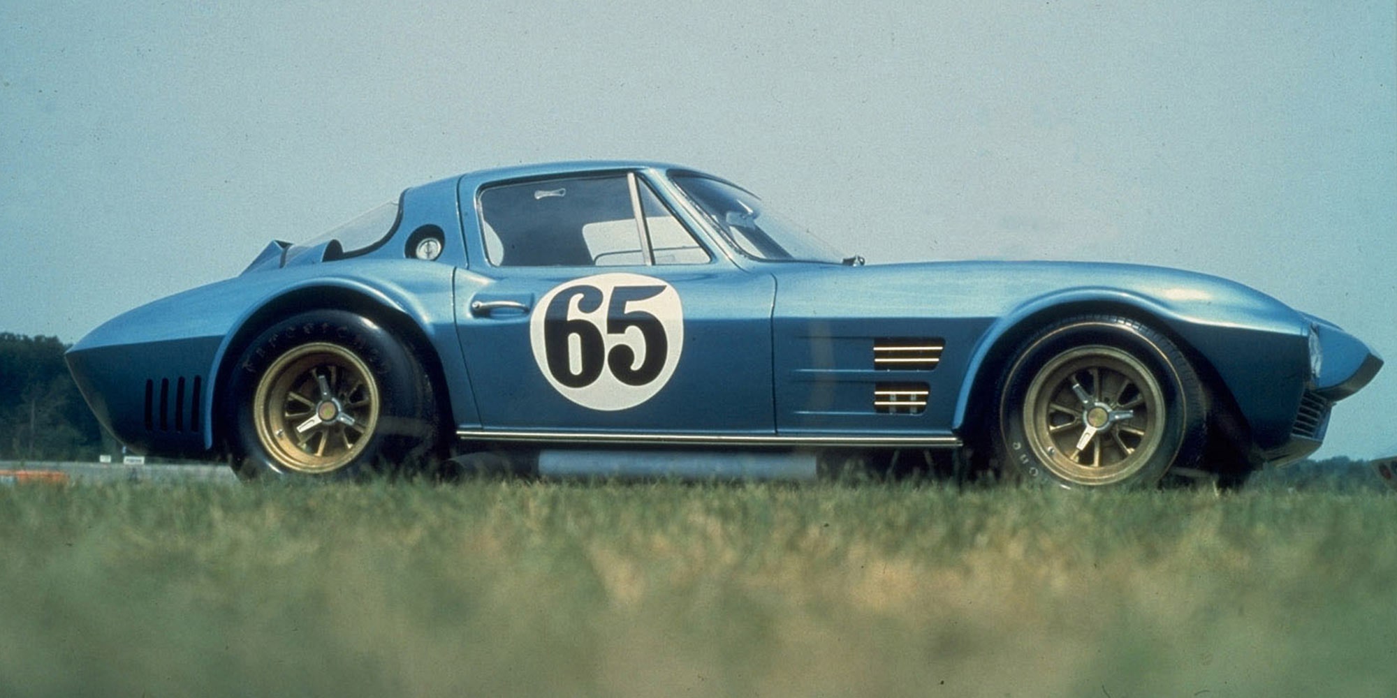 A Blue Chevrolet Corvette Race Car with Number 65 on the Door Driving on a Track.