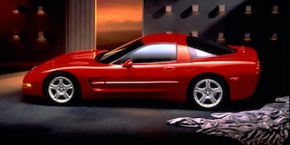 A Red Chevrolet Corvette Displayed Indoors Under Warm Lighting with Chrome Wheels.