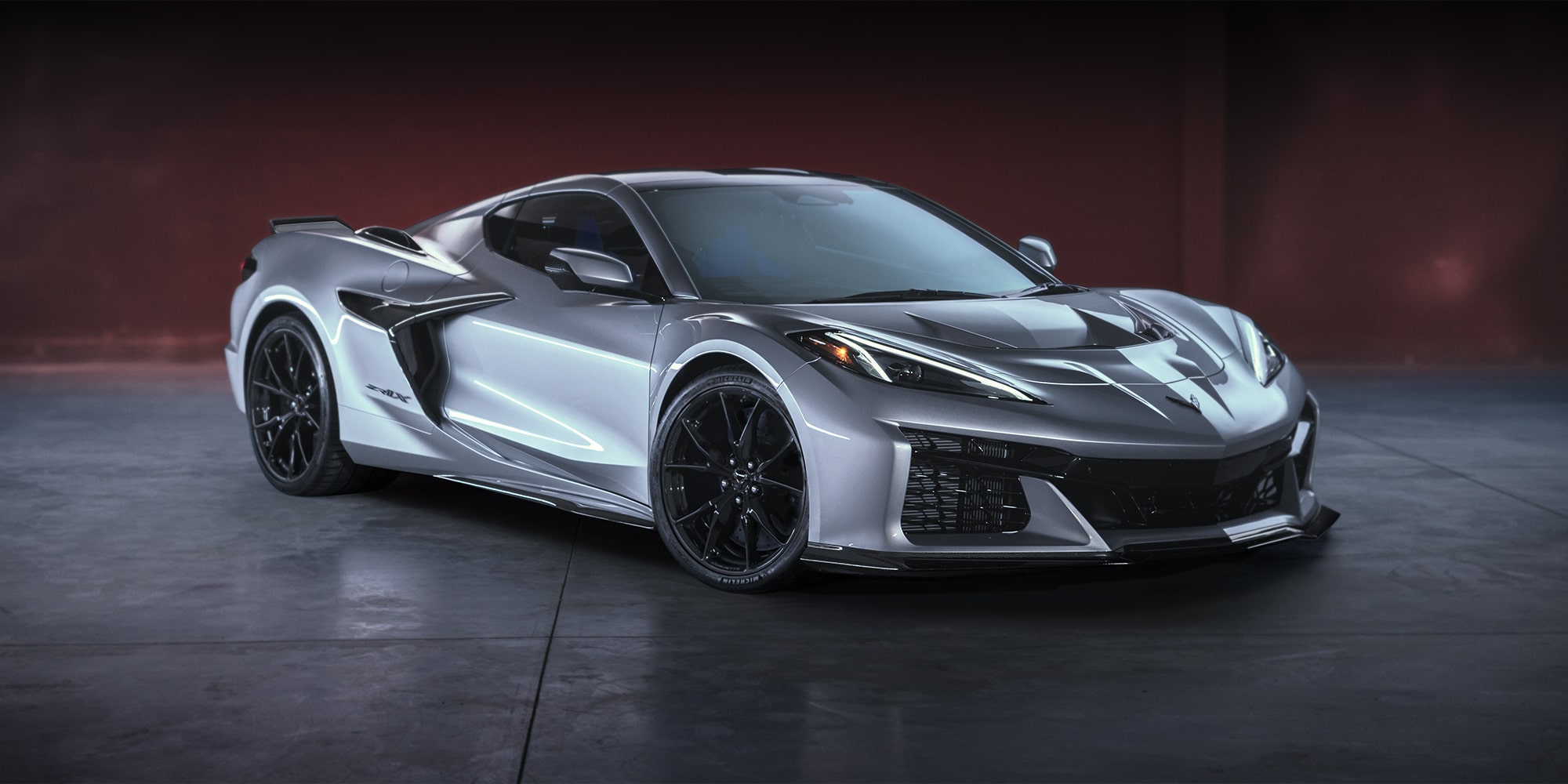 A Silver Chevrolet Corvette Z06 Displayed Indoors Under Dramatic Lighting with Glossy Black Wheels.