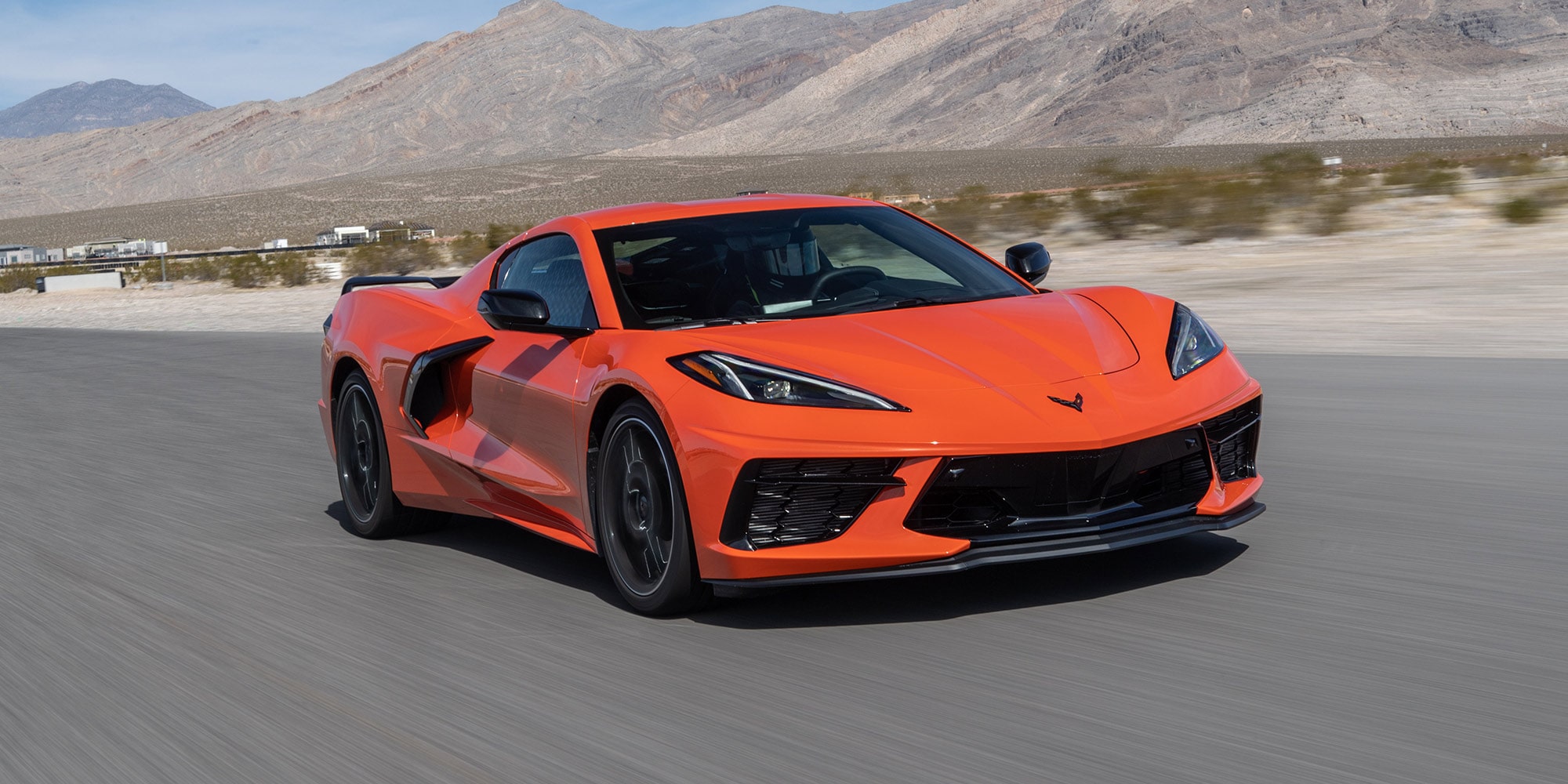 An Orange Chevrolet Corvette Z06 Sports Car Parked on a Desert Road with Aggressive Front Styling and Black Accents.