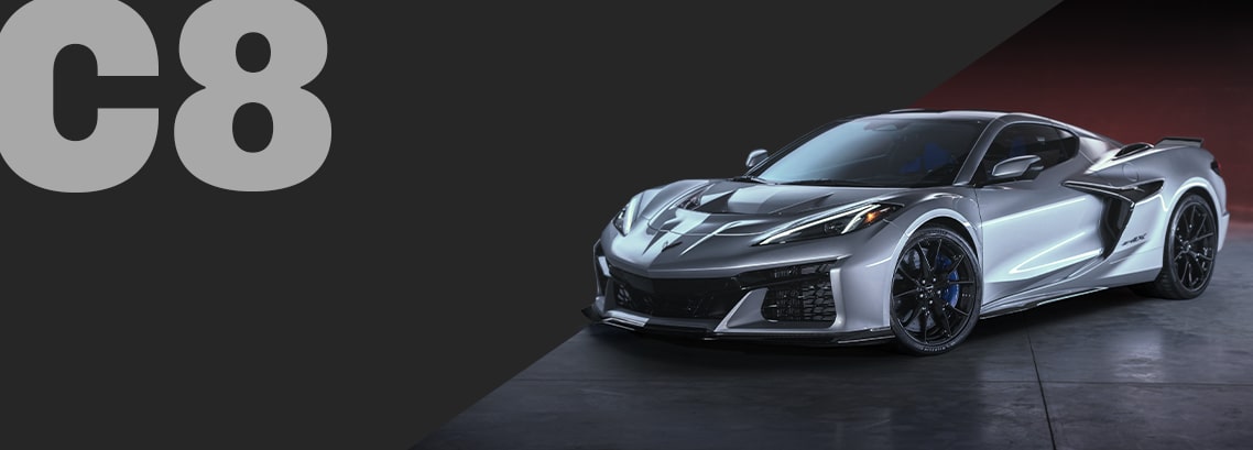 A Silver Chevrolet Corvette C8 Coupe Positioned at an Angle on a Dark Background With Large Gray Text Reading “C8.”