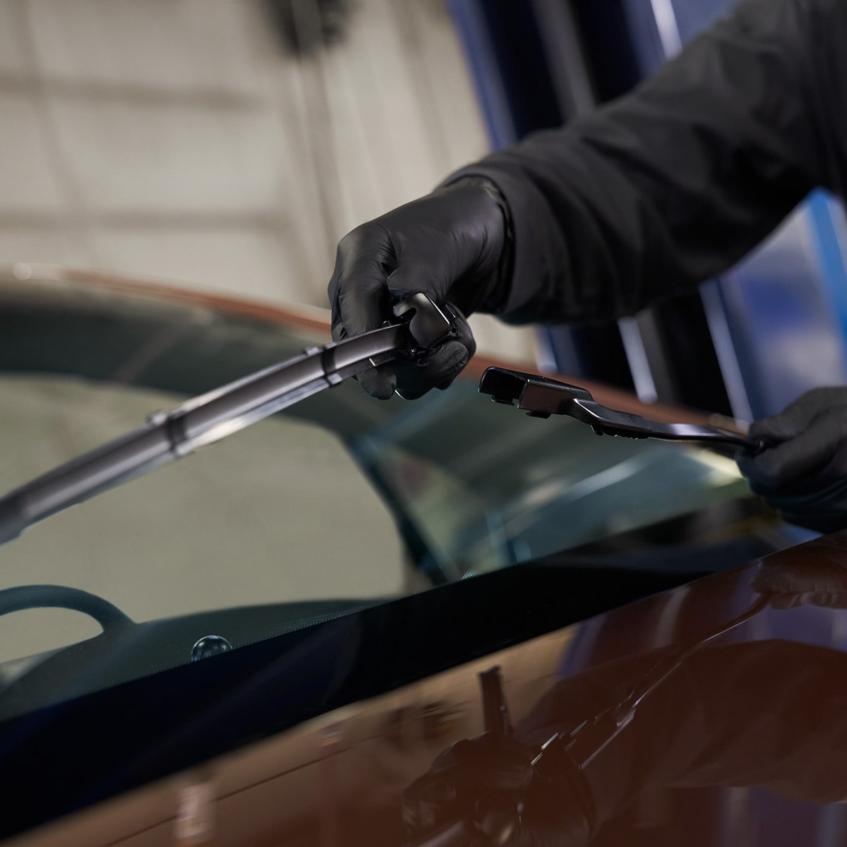 A Close-Up of a Person Using a Black Automotive Tool to Work on a Vehicle Windshield.